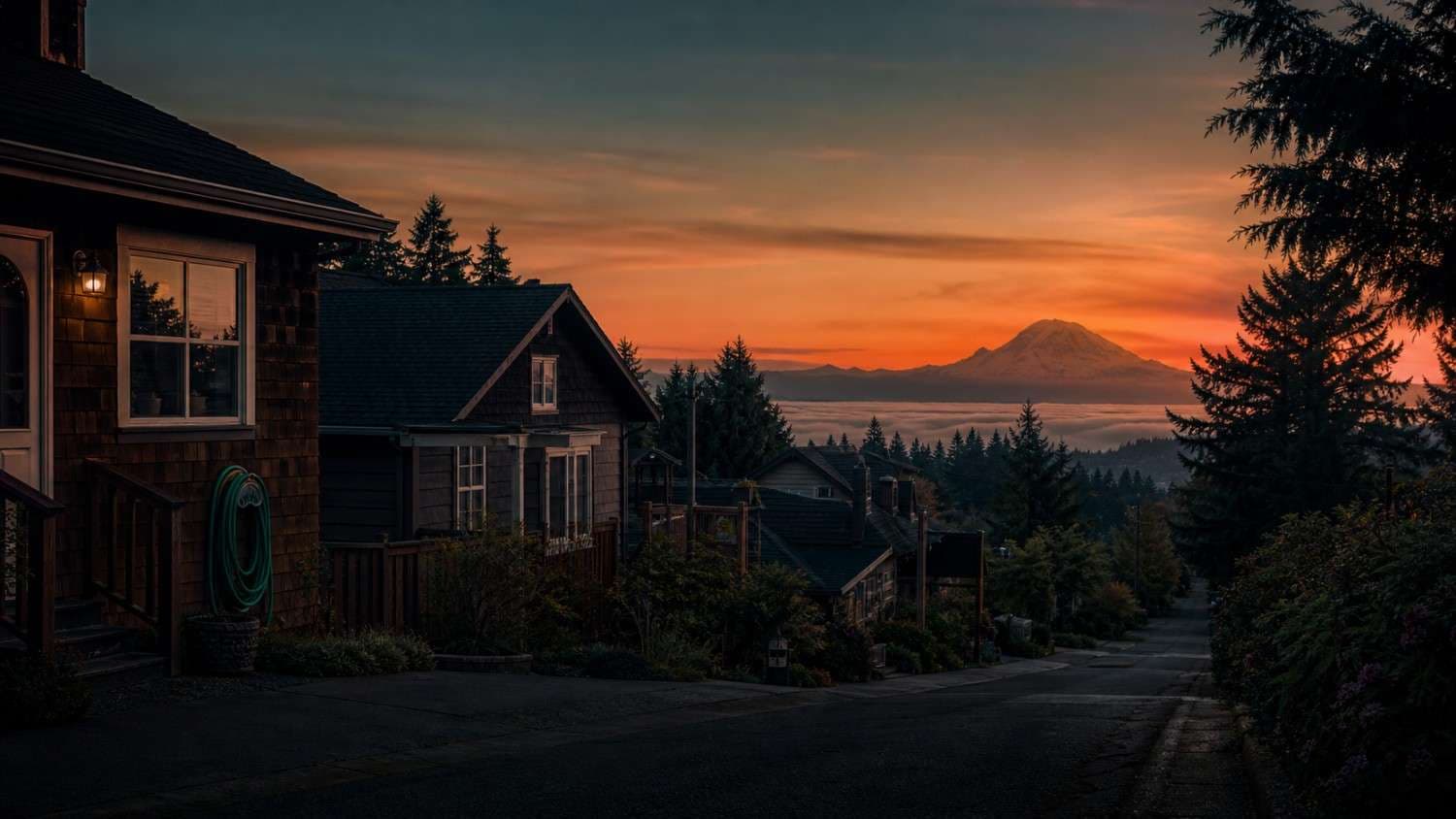 A residential care home exterior at dusk with evergreens and distant mountains